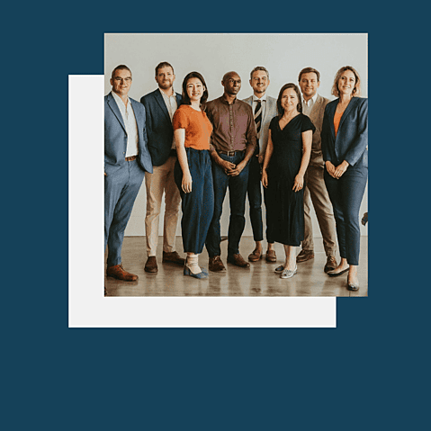 Eight business professionals standing in a line smiling